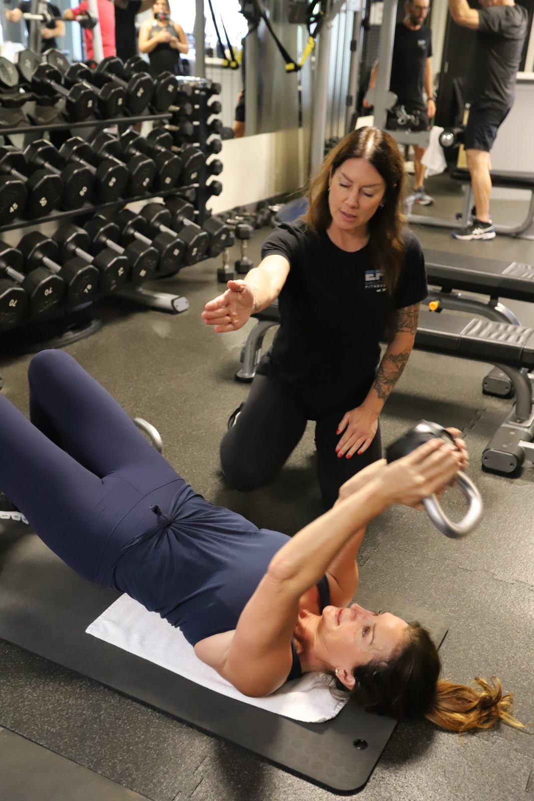 Patti Lewis coaching a client through a kettlebell press at Executive Fitness